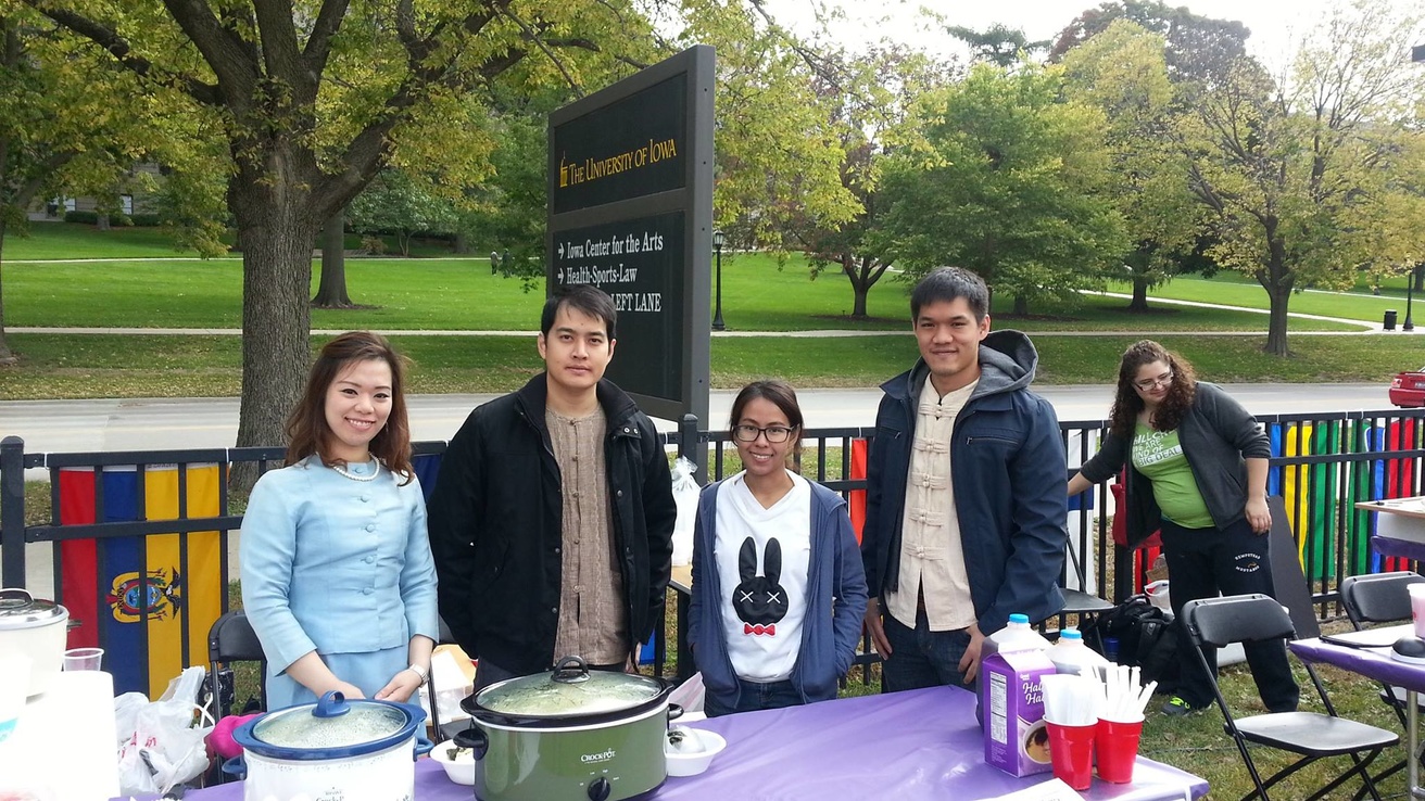 Four individuals standing behind a table with a purple table cloth